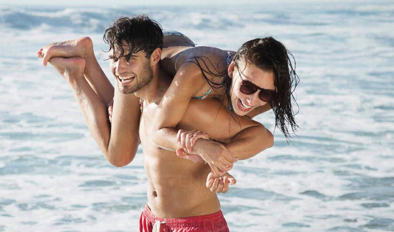Couple laughing and playing at the beach, symbolizing Ludus love